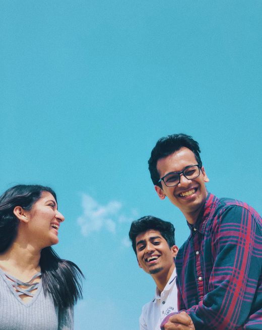 A group of laughing friends outdoors on a bright, clear day.